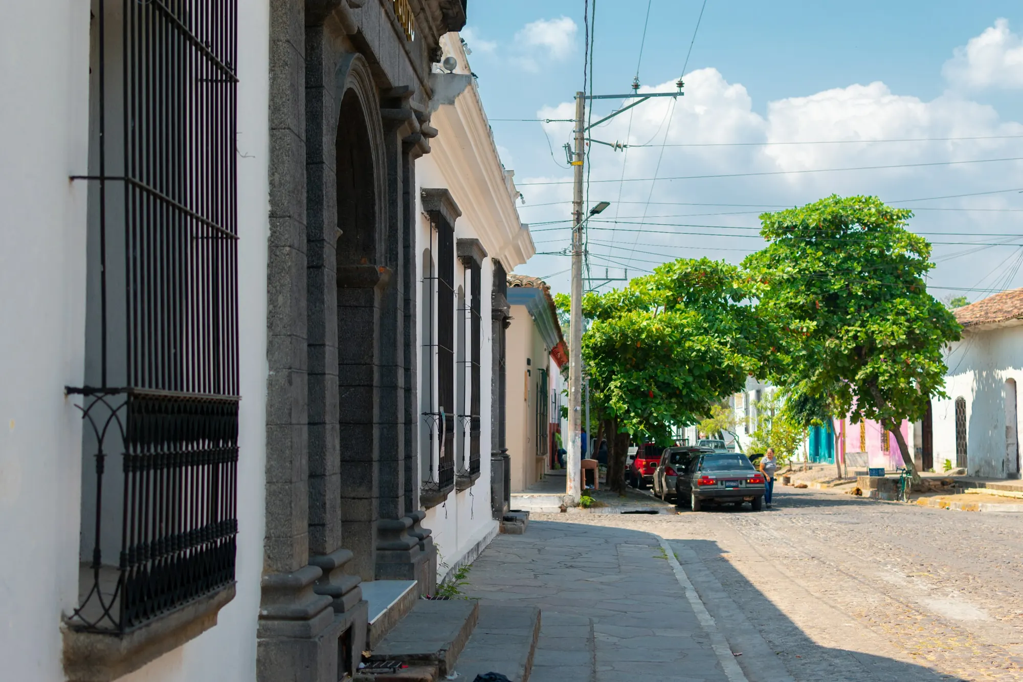 A cobbled street in Suchitoto with colonial facades and iron window grilles.
